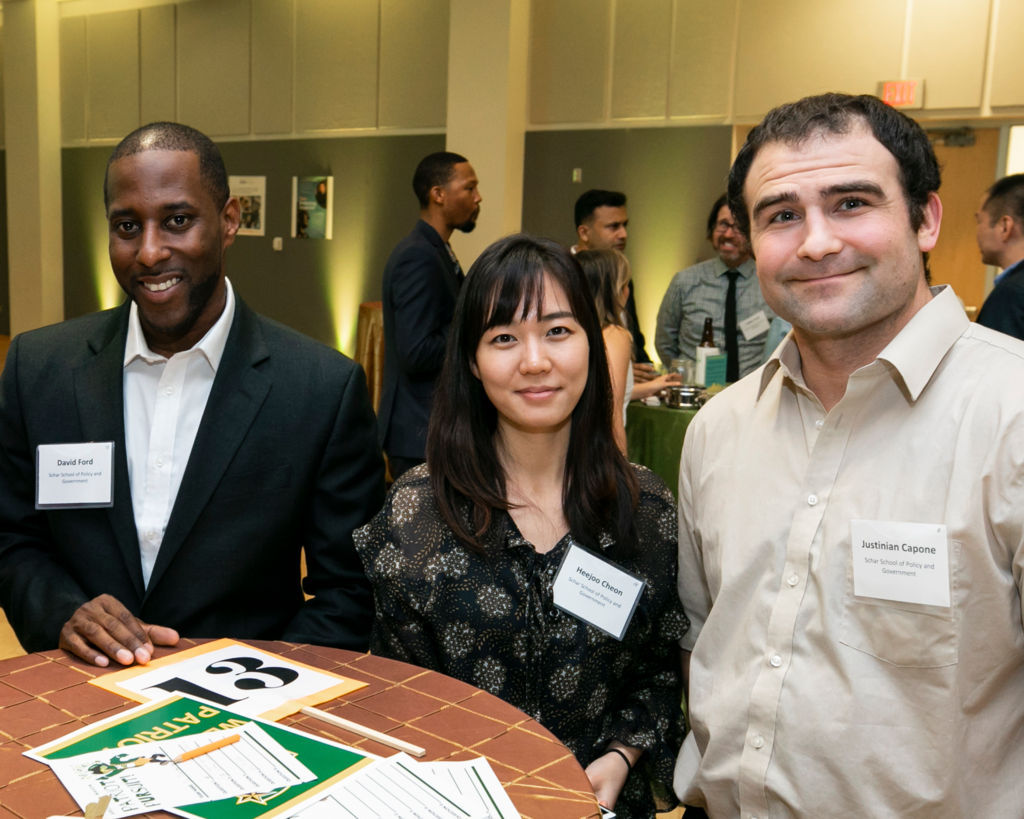 3 people facing the camera stand around a cocktail table at a Mason networking event