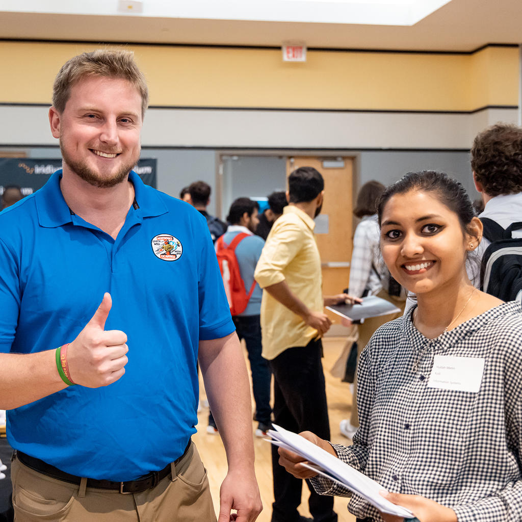 Employer gives a thumbs up while chatting with a student during a career fair at George Mason University. 
